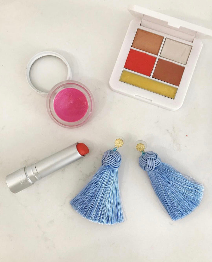 hart cornflower blue topknot tassel earrings on table with makeup