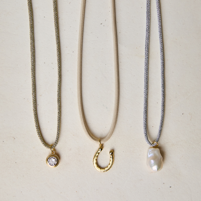 Cords with charms including gold cord, dune cord, silver cord. Bezel charm, horseshoe charm, pearl charm