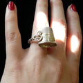 I'm all about the stories behind things worn or imperfect, for they speak of a life well-lived. A copy of a dented and lovingly used old thimble engraved with "Pearls" and resting above a twisted wire shank, accented by a little braided "eye"missing its "hook"  1--1/2" x 7/8" Size 4-10 approximately. Made in the USA. Hand signed.  Sterling Silver Dented Thimble Ring