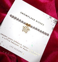 Bracelet with snowflake charm on a branded card against a red fabric background