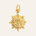 A polished gold sun charm with a smiling face and radiating rays, attached to a gold loop at the top, shown on a light cream background.