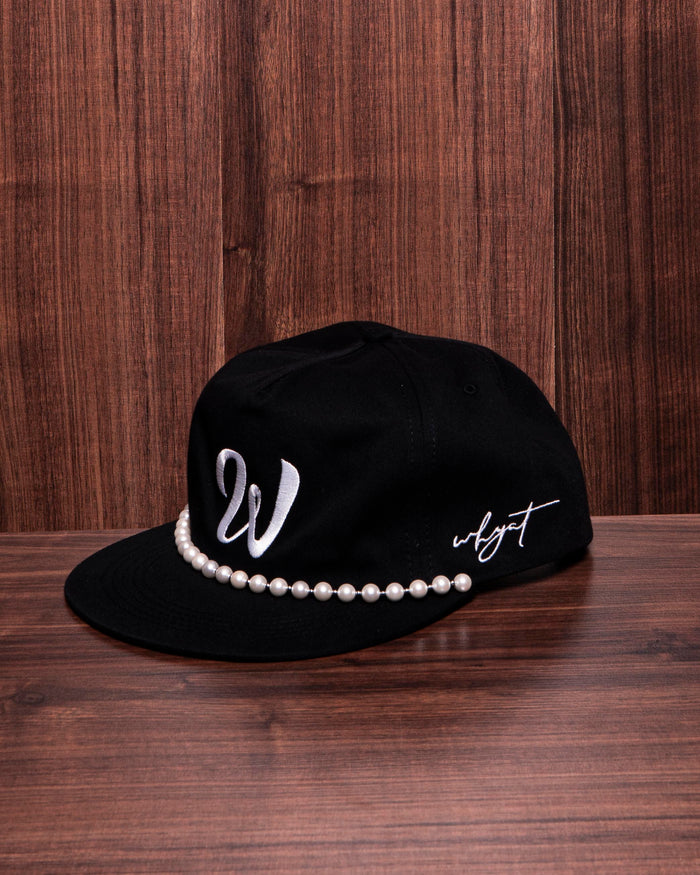 Black W cap with white embroidered ‘W’ logo and white pearl necklace