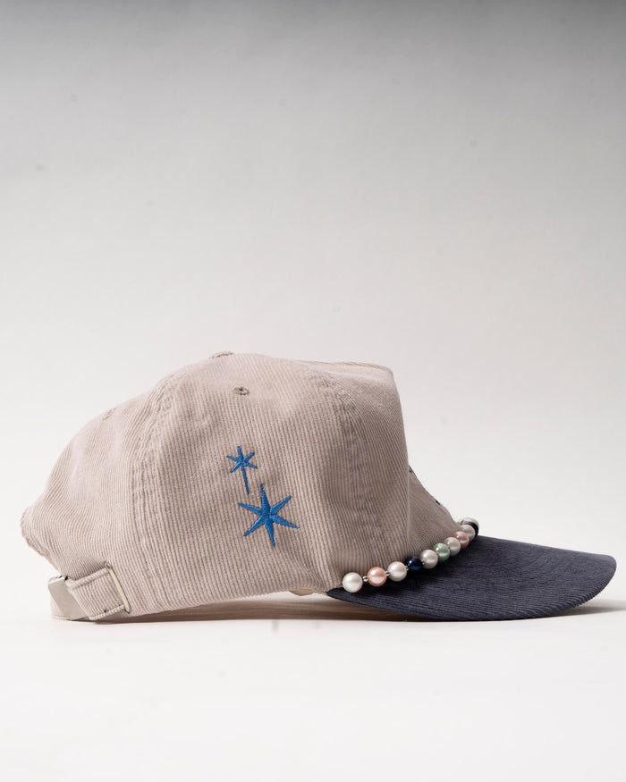 Stylische Cord-Kappe mit schwarzem W-Logo und eleganter Perlenkette.